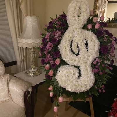 Large white floral funeral spray shaped like a ribbon with pink and purple flowers