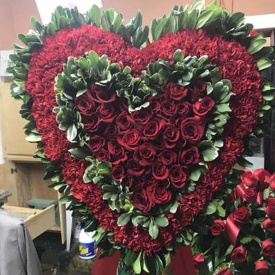 Heart-shaped red rose and carnation wreath on a stand