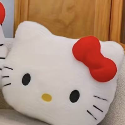 Hello Kitty plush pillow with a red bow on a bed