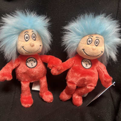 Two small plush characters with blue hair and red outfits sitting together