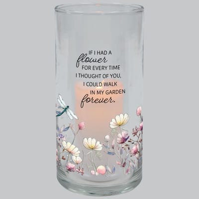 Tall clear glass candle holder with quote and pastel flower illustrations around a glowing candle