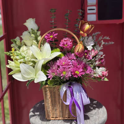 Basket arrangement of white lilies and pink daisies with a purple ribbon