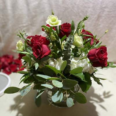 Red and white rose bouquet with eucalyptus in a low container