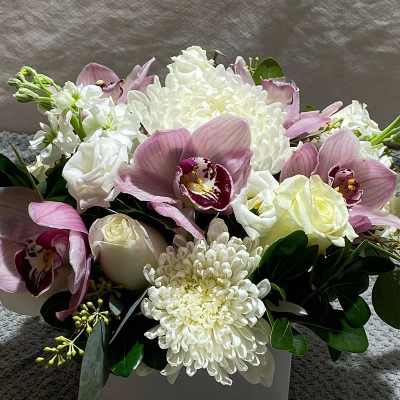 Pink orchids and white chrysanthemums in a square white vase