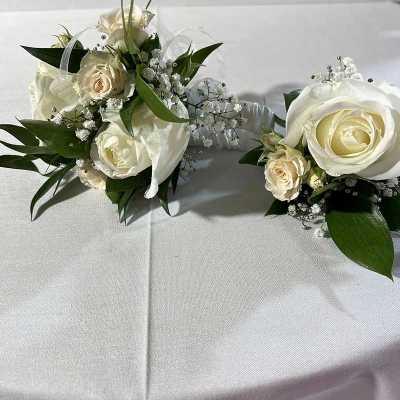 Two white rose corsages with baby's breath and ribbon accents