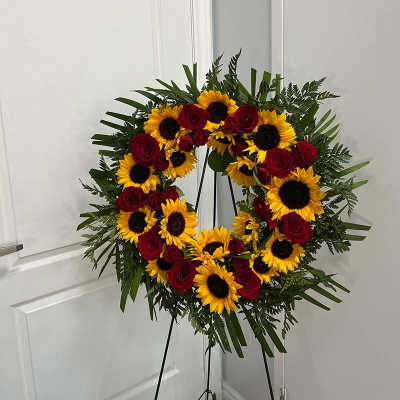Circular wreath of red roses and yellow sunflowers on a stand