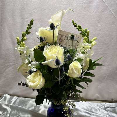 White roses and snapdragons arranged in a blue vase
