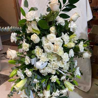 Large white floral standing spray with roses, lilies, and carnations