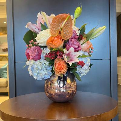 Mixed bouquet of roses, lilies, hydrangeas, and anthurium in a glass vase
