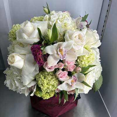 White roses and orchids arranged in a magenta box