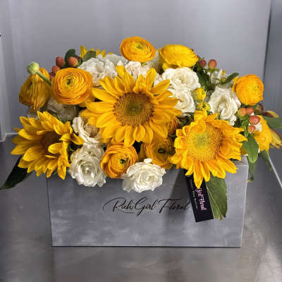 Yellow sunflowers and white blooms arranged in a gray box