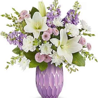 White lilies and purple flowers arranged in a lavender vase