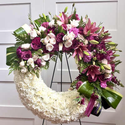 Large crescent floral wreath with pink and white flowers on a stand