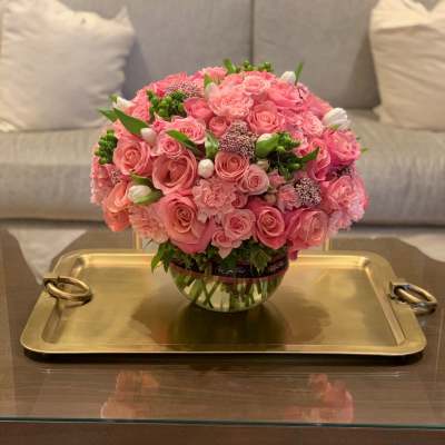 Pink rose bouquet in a clear glass vase on a gold tray