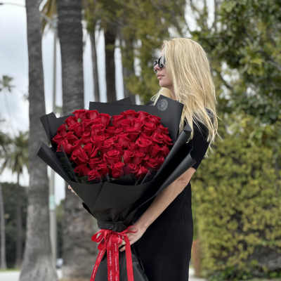 Large bouquet of red roses wrapped in black paper with a red ribbon