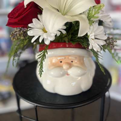 Red roses and white lilies arranged in a Santa face container