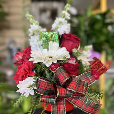 Red and white floral arrangement in a red container with a plaid bow