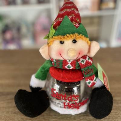 Elf plush sitting on a jar labeled Santa's Helper