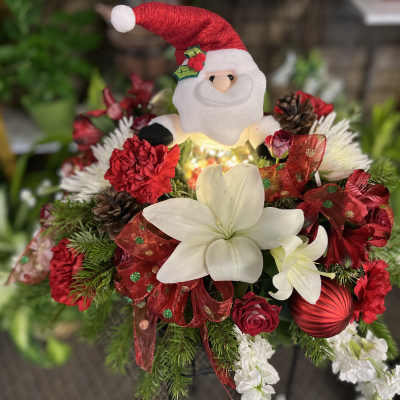 Christmas bouquet with a Santa plush, white lilies, red carnations, and ribbon