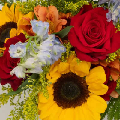 Bouquet of red roses and yellow sunflowers with blue flowers
