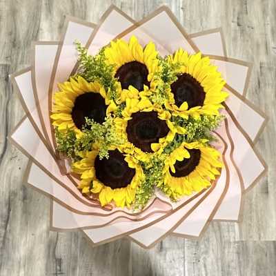 Bouquet of sunflowers wrapped in pale pink paper