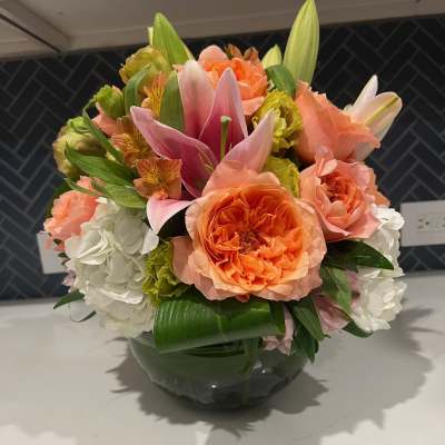 Bouquet of orange and pink flowers in a glass bowl vase