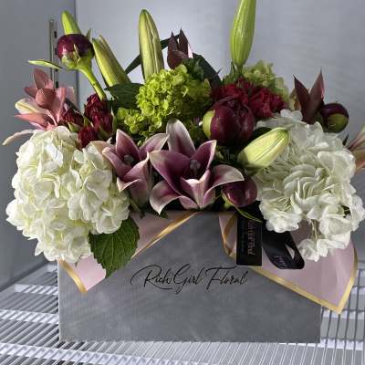 Box arrangement of white hydrangeas, burgundy calla lilies, and lily buds
