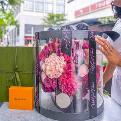 Pink and blush flowers arranged in a round black gift box with ribbon