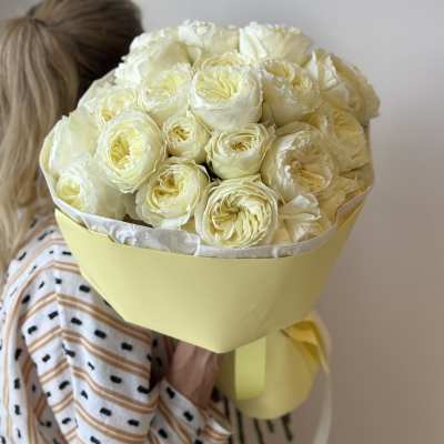 Bouquet of pale cream roses wrapped in yellow paper