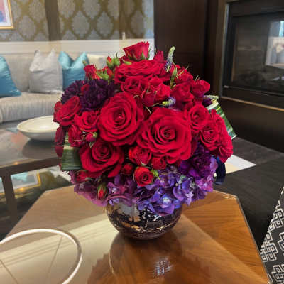 Red roses and purple hydrangeas arranged in a decorative vase