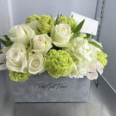 White roses and green hydrangeas arranged in a gray gift box