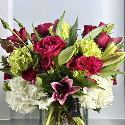Square vase arrangement with hot pink roses, white hydrangeas, green blooms and pink lilies