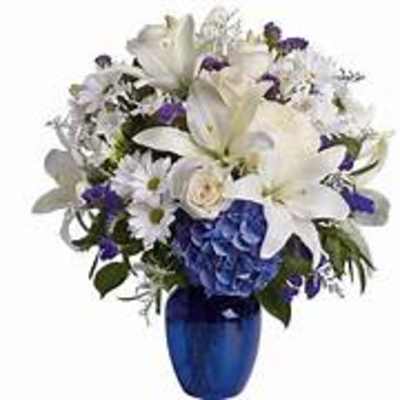 White and purple floral arrangement in a blue vase