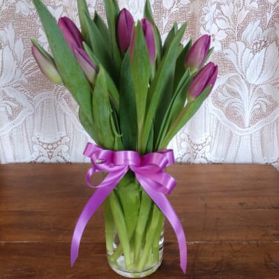 Purple tulip bouquet tied with a satin ribbon in a clear glass vase