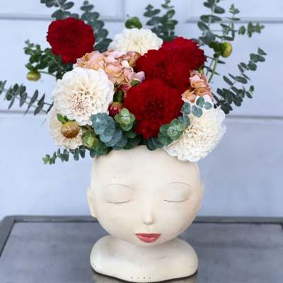 Flower crown of red, white, and peach blooms on a mannequin head