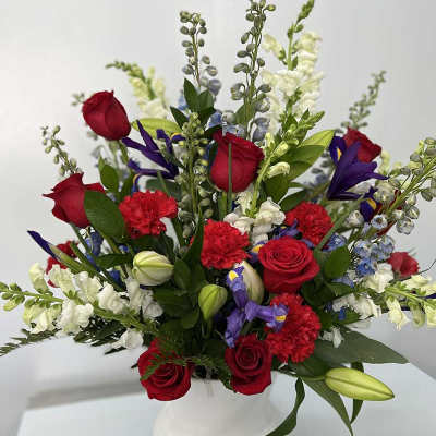Red roses, white snapdragons, and purple flowers in a white vase