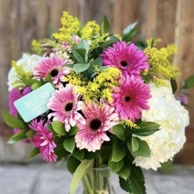 Bouquet of pink gerbera daisies and white hydrangeas in a glass vase
