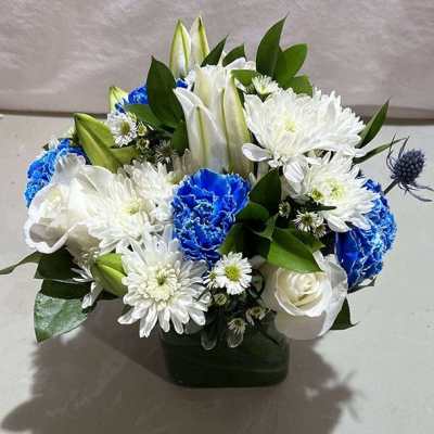 Blue and white flower arrangement in a dark green vase