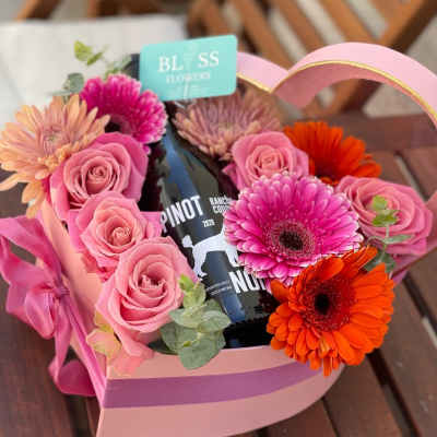 Pink flower box with roses and gerbera daisies around a wine bottle