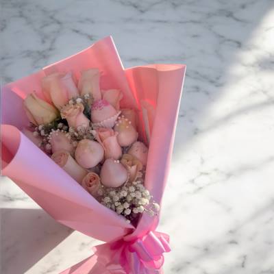Pink bouquet of roses with small white filler flowers in pink wrapping