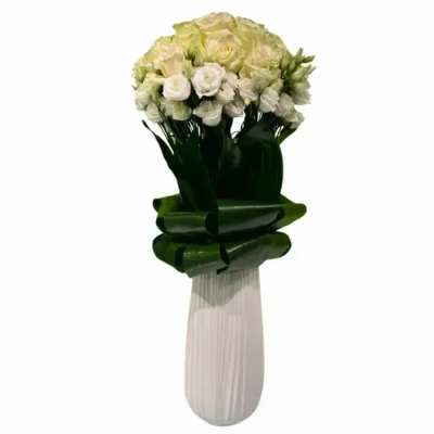Bouquet of white and pale yellow roses in a tall wrapped vase