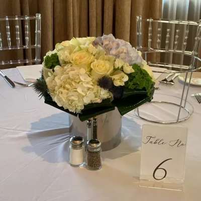 Round white and pale yellow floral centerpiece on a table with a number card