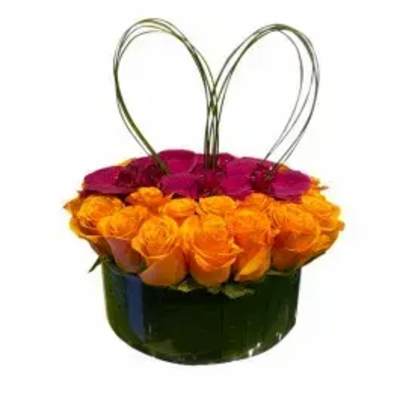 Round box of orange and magenta roses with wire heart handles