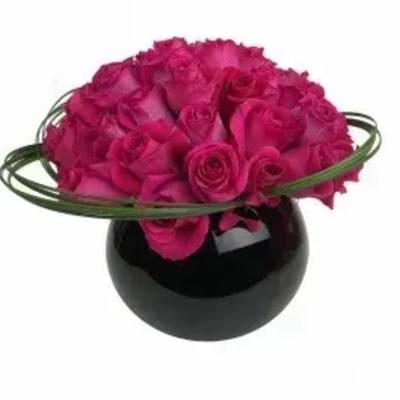 Hot pink rose arrangement in a black round vase with green loops