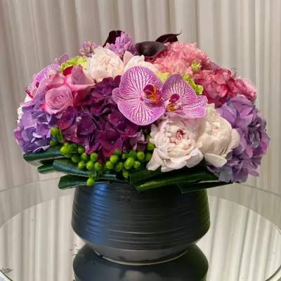 Pink and purple floral arrangement in a black vase