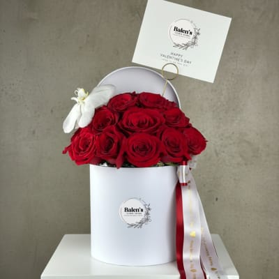 Red roses in a white hatbox with a Valentine card and ribbon