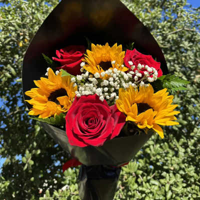 Bouquet of red roses and yellow sunflowers wrapped in black paper