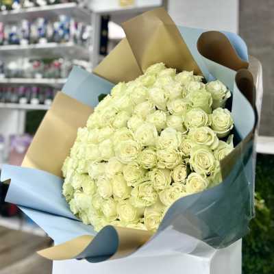 Large bouquet of pale cream roses wrapped in blue and tan paper