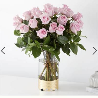 Pink roses arranged in a clear glass vase with a gold base
