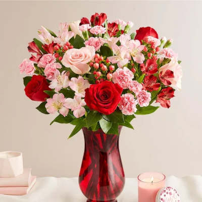 Bouquet of red and pink flowers in a red glass vase